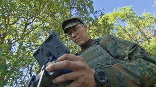Junger Soldat in Felduniform steuert eine Drohne
