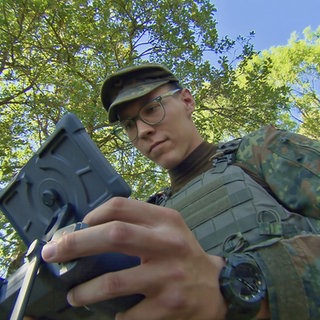 Junger Soldat in Felduniform steuert eine Drohne
