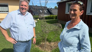Manfred Bauer 8l.) und Andrea Thome rahmen die Statue von Hirsch Henry ein