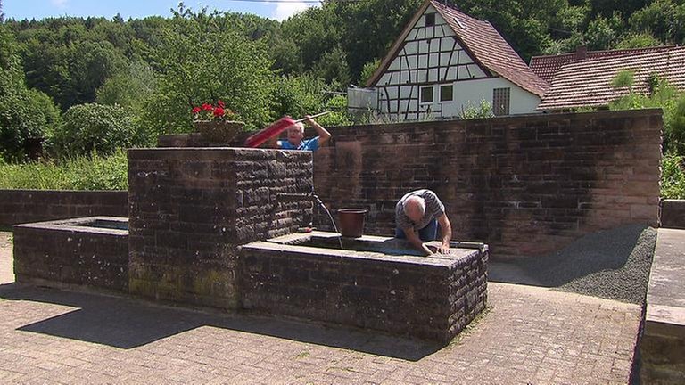 Männer säubern Brunnen