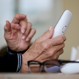 Eine ältere Person hält einen Telefonhörer in der Hand