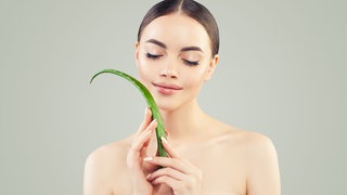 Frau mit Aloe-Vera-Blatt in der Hand