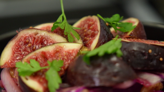 Eine Schale mit angerichtetem Rotkohlsalat, auf dem frische Feigen liegen. 