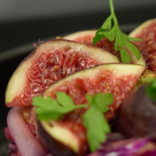 Eine Schale mit angerichtetem Rotkohlsalat, auf dem frische Feigen liegen. 