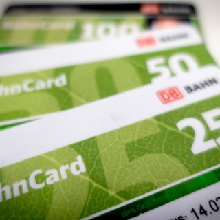 Auf einem Tisch liegen übereinander eine Bahncard 25, eine Bahncard 50 und eine Bahncard 100.