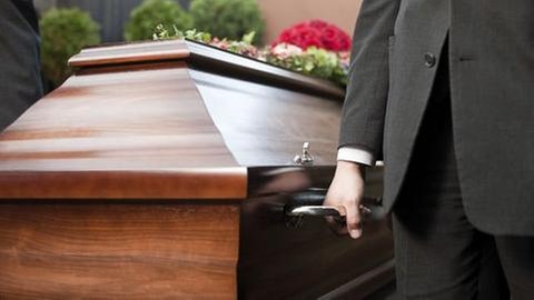 Ein Mann trägt einen Sarg.