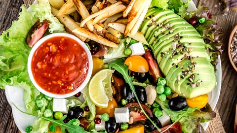 Teller mit frischen vegetarischen Lebensmitteln wie Gemüse, Kräutern und Saaten. Was kann man bei Eisenmangel tun?