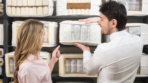 Verkäufer zeigt Kundin verschiedene Matratzen