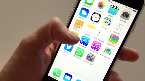 Auf dem Display eines Apple iPhone sind Symbole verschiedener Apps zu sehen. 