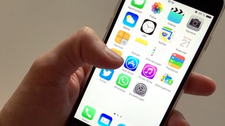 Auf dem Display eines Apple iPhone sind Symbole verschiedener Apps zu sehen. 