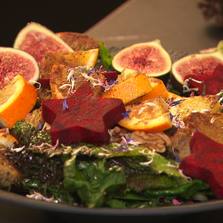 Ein Wildkräutersalat ist schön auf einem Teller angerichtet. Die rote Beete ist in Sternen geschnitten.