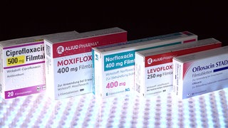 Medikamenten-Packungen der Fluorchinolon-Antibiotika Ciprofloxacin, Levofloxacin, Moxifloxacin, Norfloxacin und Ofloxacin stehen auf einer Oberfläche.