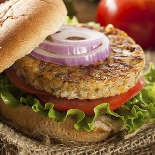 Ein gegrillter Tofu-Burg auf einem Brötchen mit Tomaten, Zwiebeln und Salat.