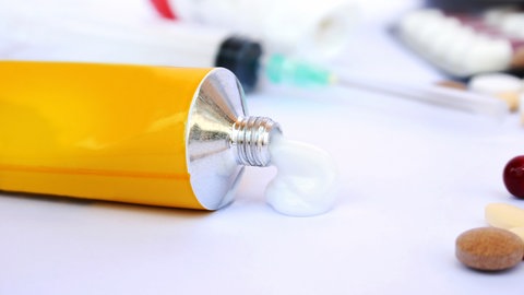 Eine offene Tube Creme liegt auf einem Tisch.