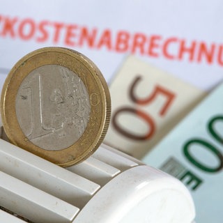 Eine Euromünze in einem Heizungsthermostat, der auf Heizkostenabrechnungen und Euro-Geldscheinen liegt. Inflation und Explosion der Preise: Dieses Jahr werden viele Mieter bei den Nebenkosten nachzahlen müssen. So prüft man die Abrechnung.