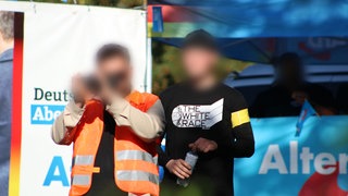 Zwei verpixelte Männer vor dem AfD-Stand