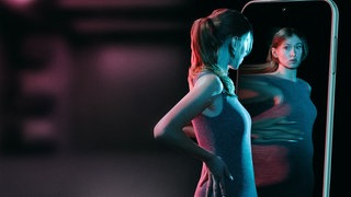 Junge schlanke Frau steht vor Spiegel und nimmt ihren Körper verzerrt wahr