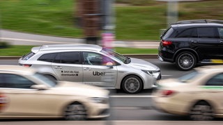 Auto mit der Aufschrift "Uber" überholt ein Taxi