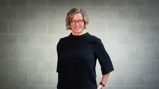 Ulrike Heine mit Mauer im Hintergrund