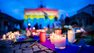 Blumen und Kerzen zum Gedenken an die Opfer des Terroranschlags auf den CSD vor dem Brandenburger Tor