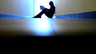 Mann sitzt mit Laptop auf dem Boden