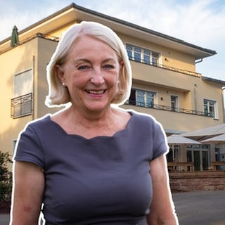 Blonde mittelalte Frau vor riesiger Fertighaus-Villa