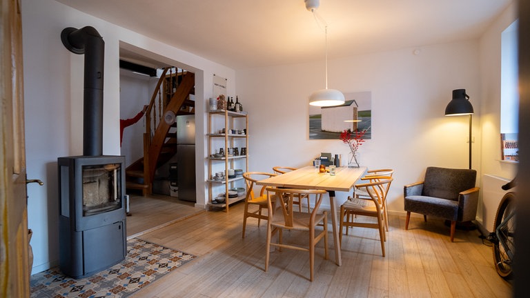 Das offene Wohnzimmer mit Dielenboden, schönem Esstisch und Holzofen.