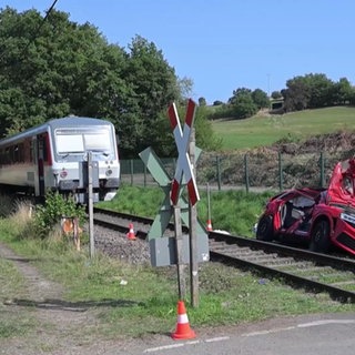 Ein Unfallwagen steht neben Bahngleisen und ein paar Meter weiter steht ein Zug
