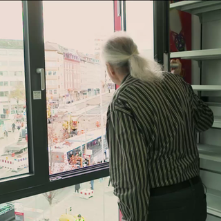 Mann blickt aus Ladenfenster