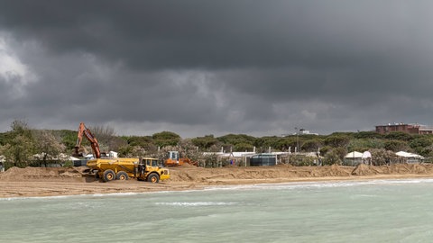 Bagger und LKW verteilen neuen Sand am Strand von Lido di Jesolo in Venedig
